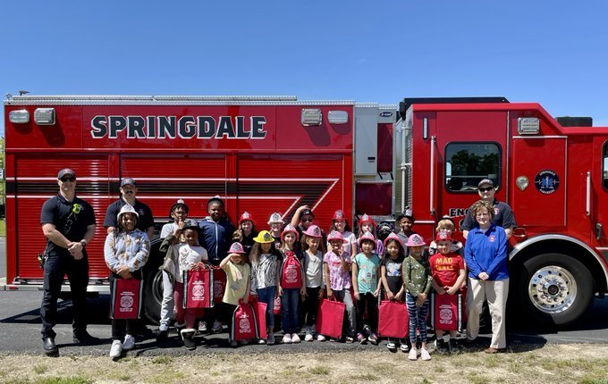Photo of students infront of a firetruck with the fire fighters