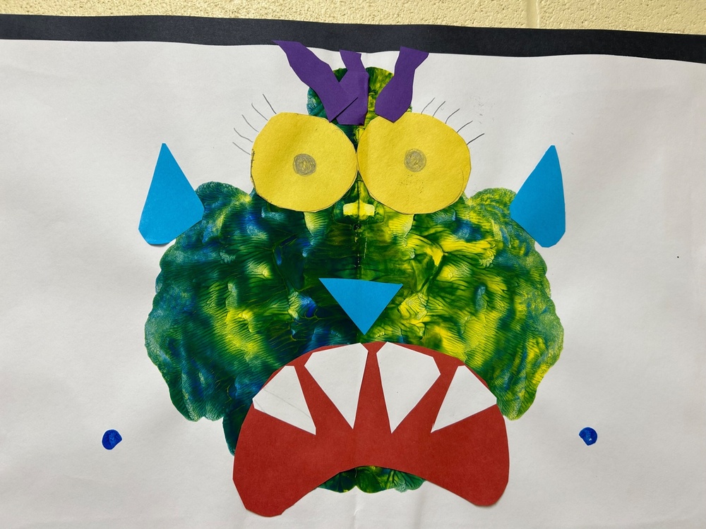 photo of  a student painting, big green monster, very white teeth